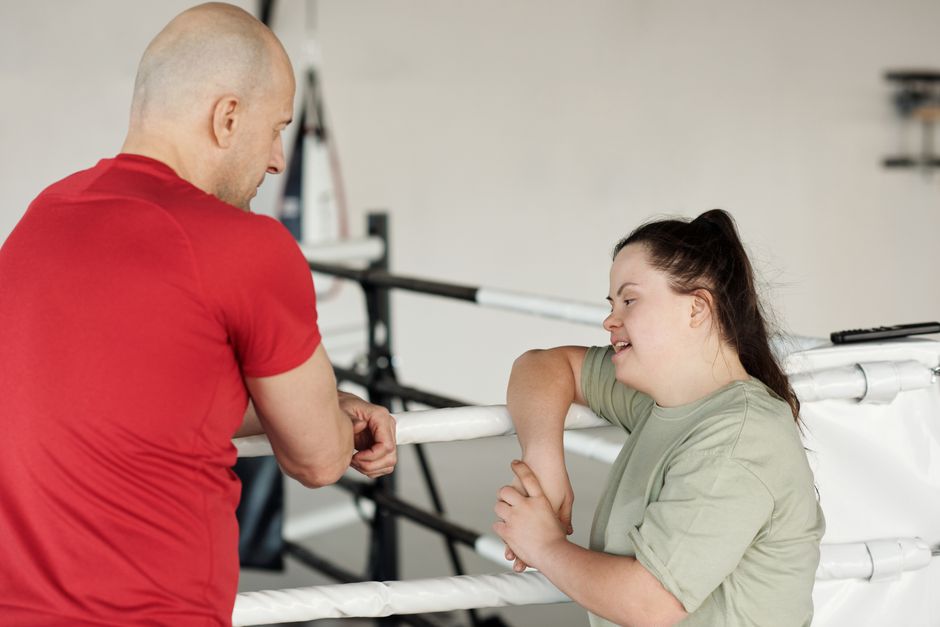 Two people engage in a supportive conversation in a boxing gym.